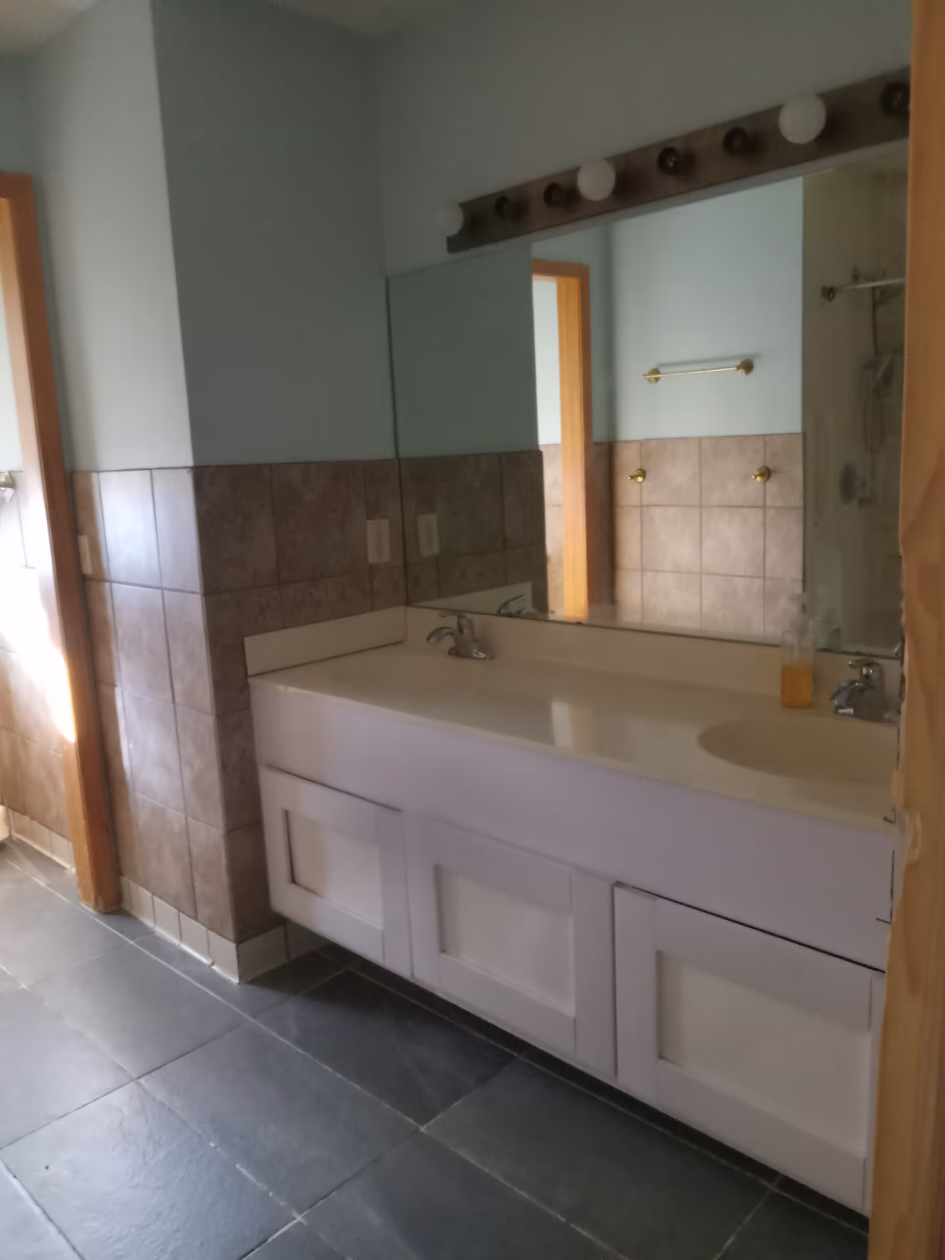 Public bathroom vanity with double sinks, large mirror, and tiled walls.