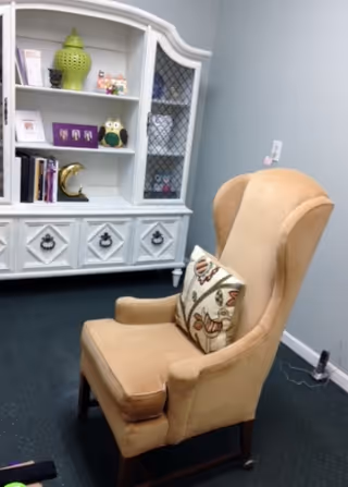 Beige armchair with cushion beside a white cabinet in a cozy living room.