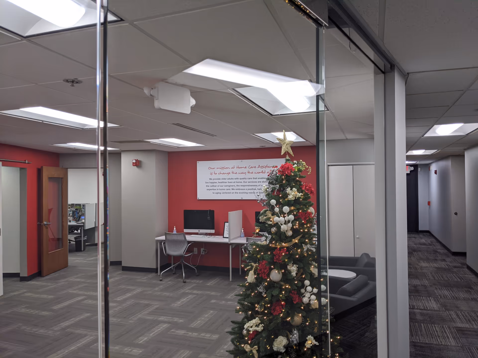 Office-like lobby area with desks, glass partitions, and a decorated Christmas tree.
