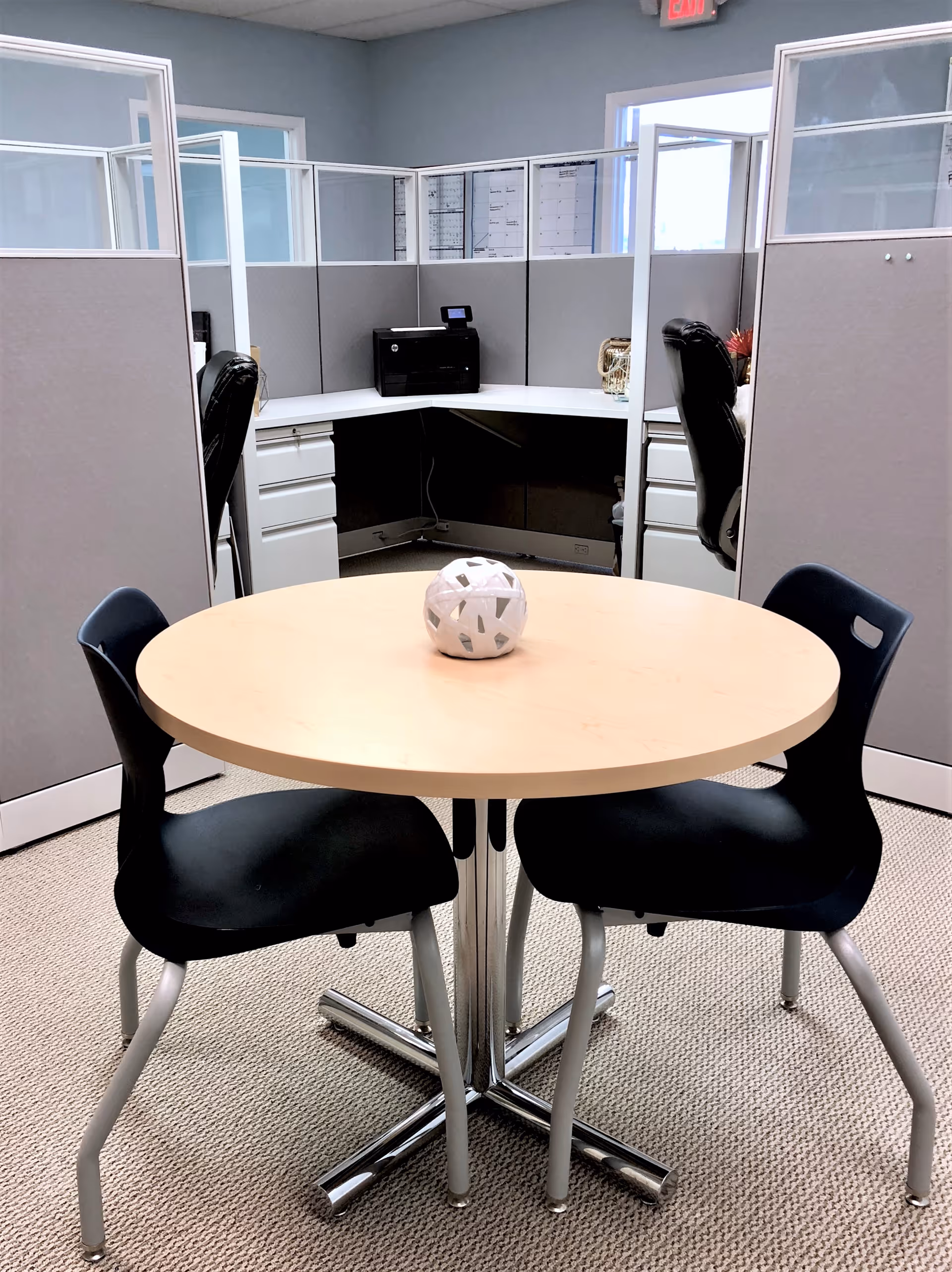 Round table with four black chairs in a cubicle office area