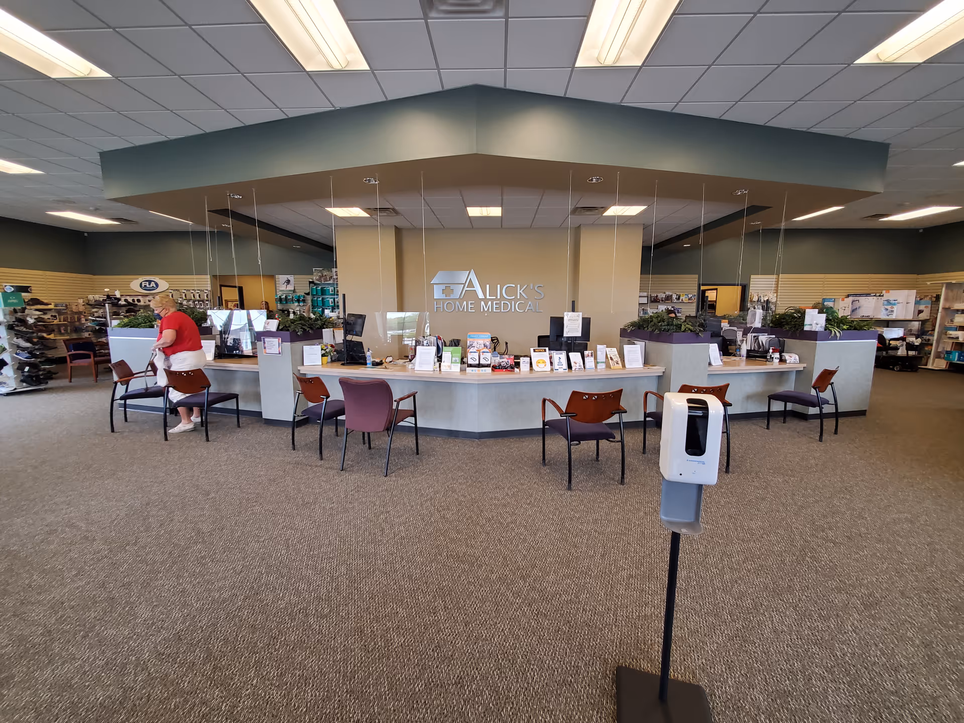 Spacious lobby with curved reception desk labeled Alick's Home Medical and seating.