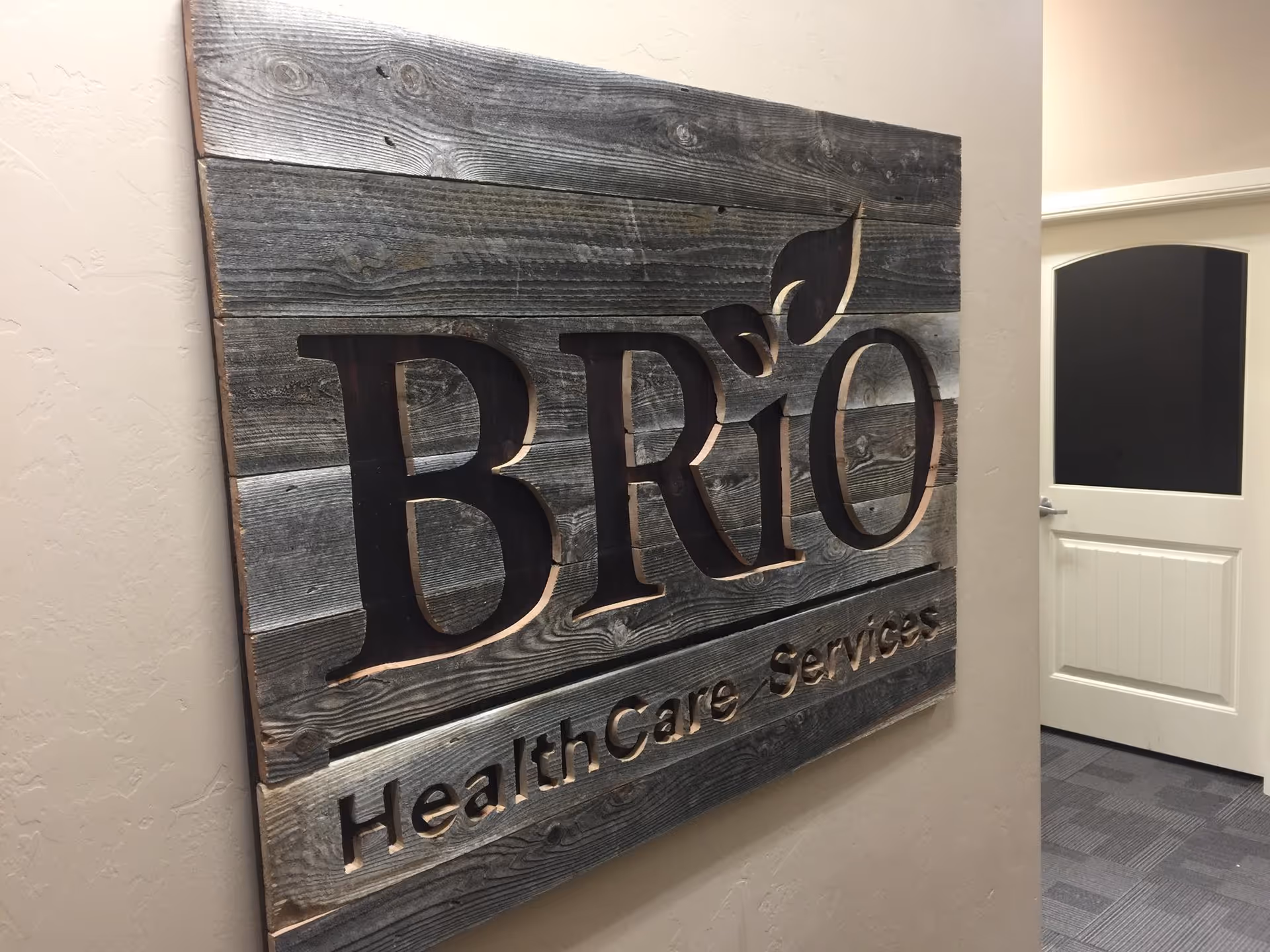 Wooden BRiO Health Care Services sign mounted on an interior wall.