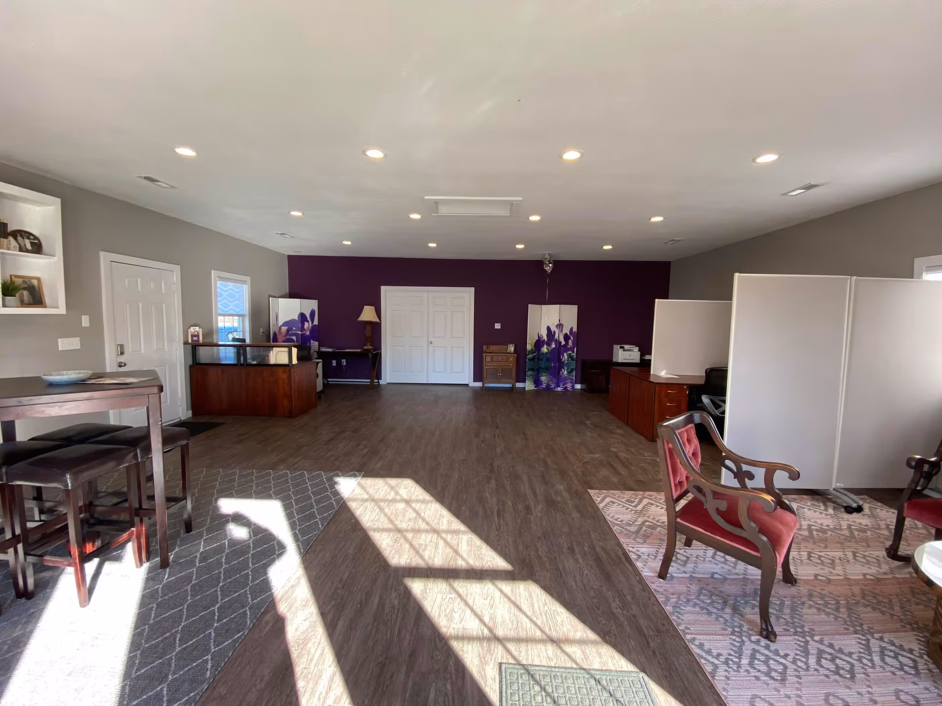 Spacious senior living lounge with a purple accent wall and furniture.