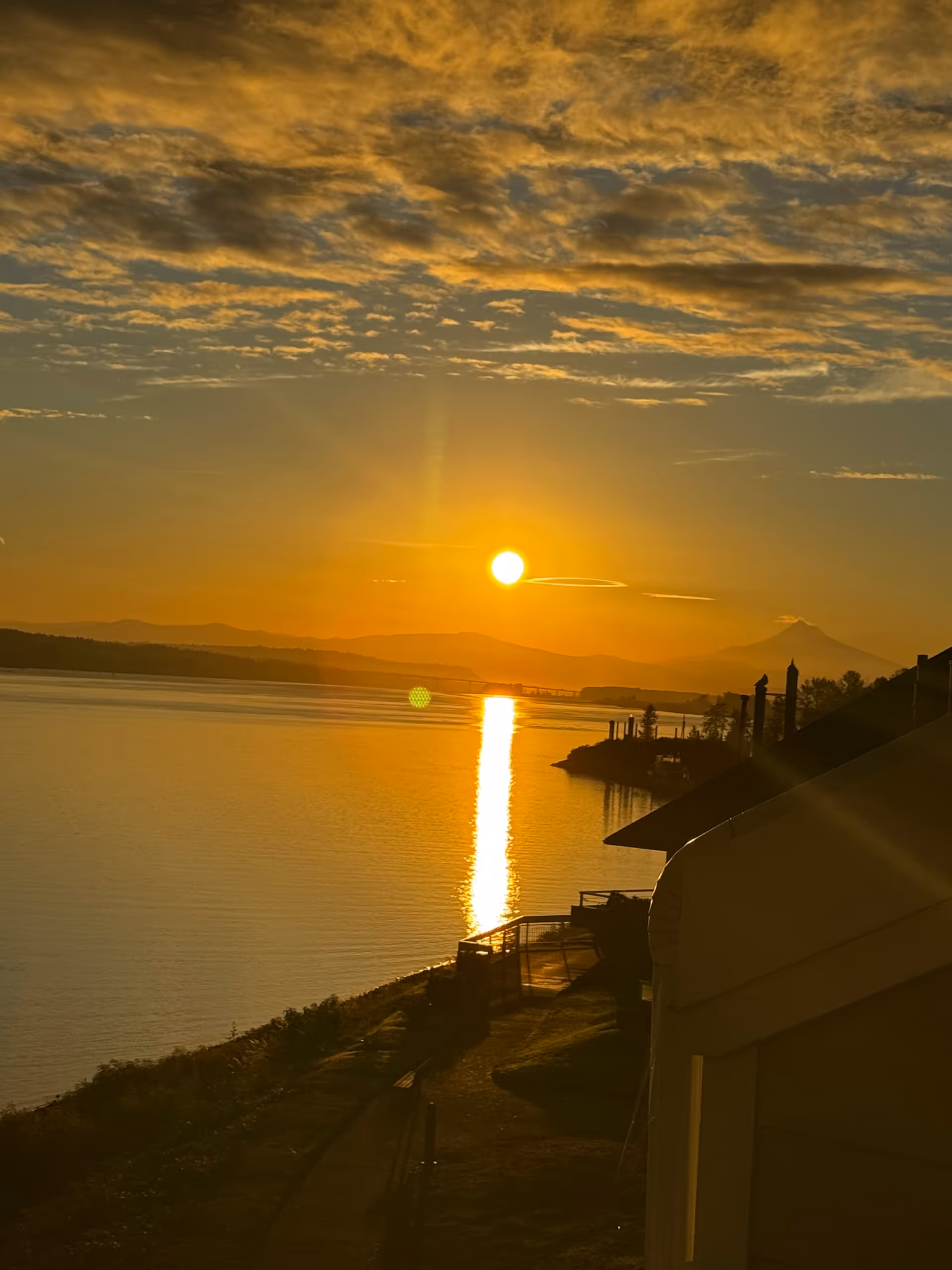 Golden sunset over a lake with a railing path and building edge in foreground