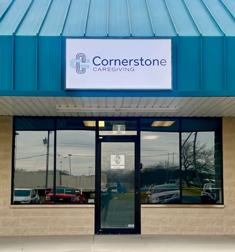 Front entrance of Cornerstone Caregiving with teal awning, glass doors, and sign.