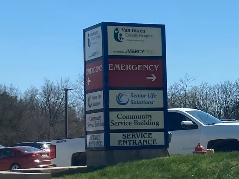 A tall outdoor sign for Van Buren County Hospital with emergency and service entrance directions.