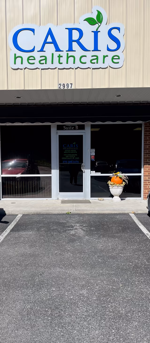 Caris Healthcare storefront with glass doors, entrance sign, and a decorative pumpkin planter.