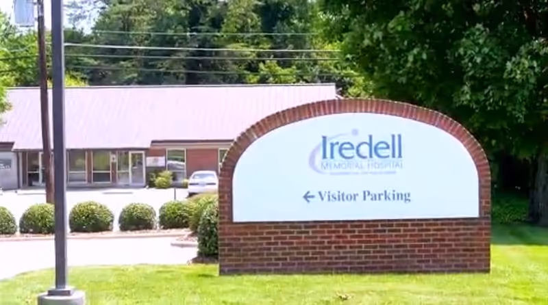 Exterior view of Iredell Health System facility with a visitor parking sign.