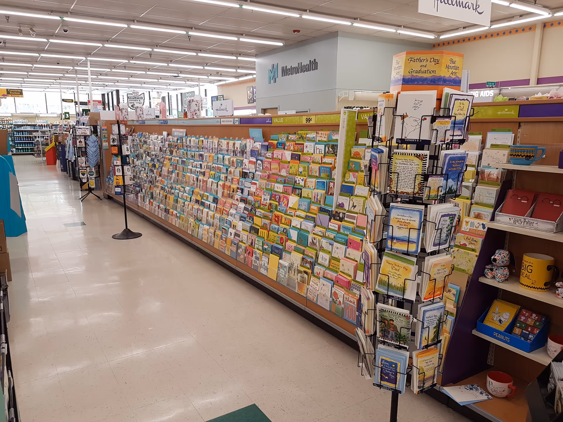 A long aisle of colorful greeting cards fills a Discount Drug Mart store interior.