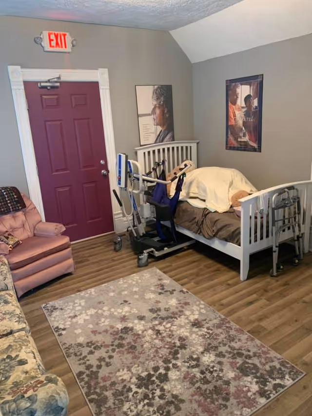 A furnished senior living bedroom with a hospital-style bed and medical equipment.