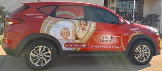 Red SYNERGY HomeCare van parked outdoors with branding and contact information.