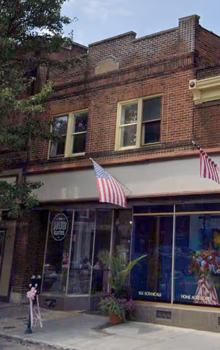 Facade of Village Caregiving storefront, brick building with large windows and flags.