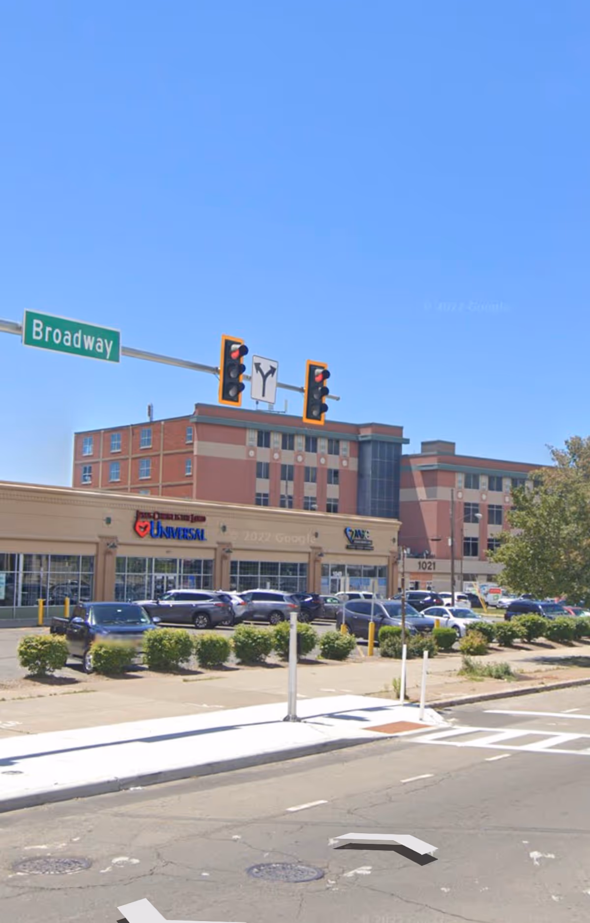 Exterior street view with Broadway sign, traffic lights, and a shopping plaza.
