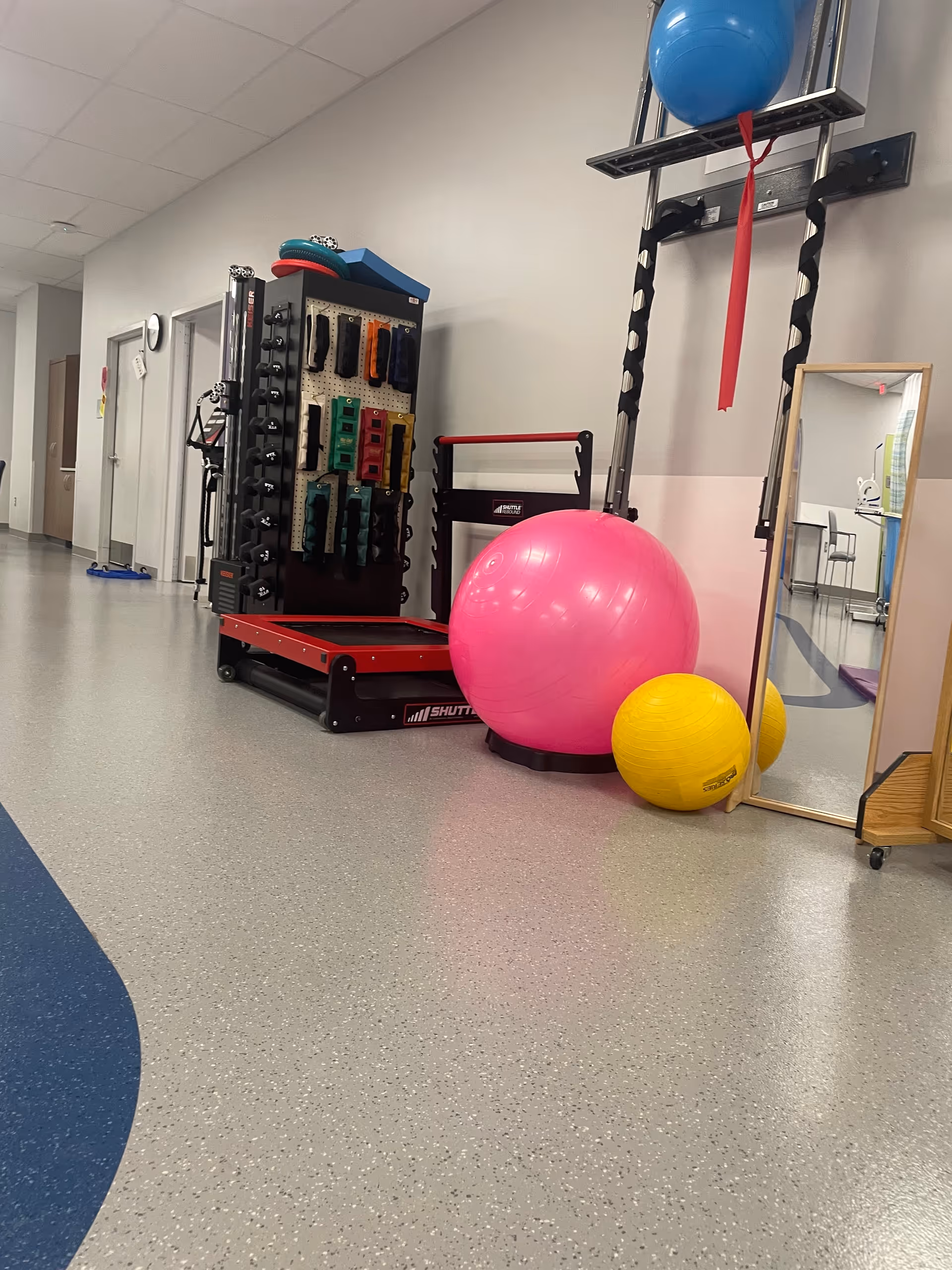 Indoor gym area with exercise equipment, balance balls, and a mirror.