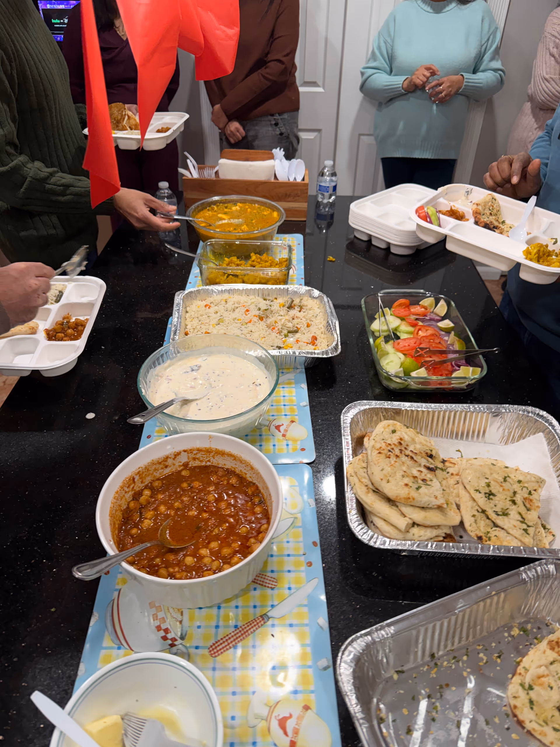 Residents serve themselves from a buffet-style meal at a communal dining table.