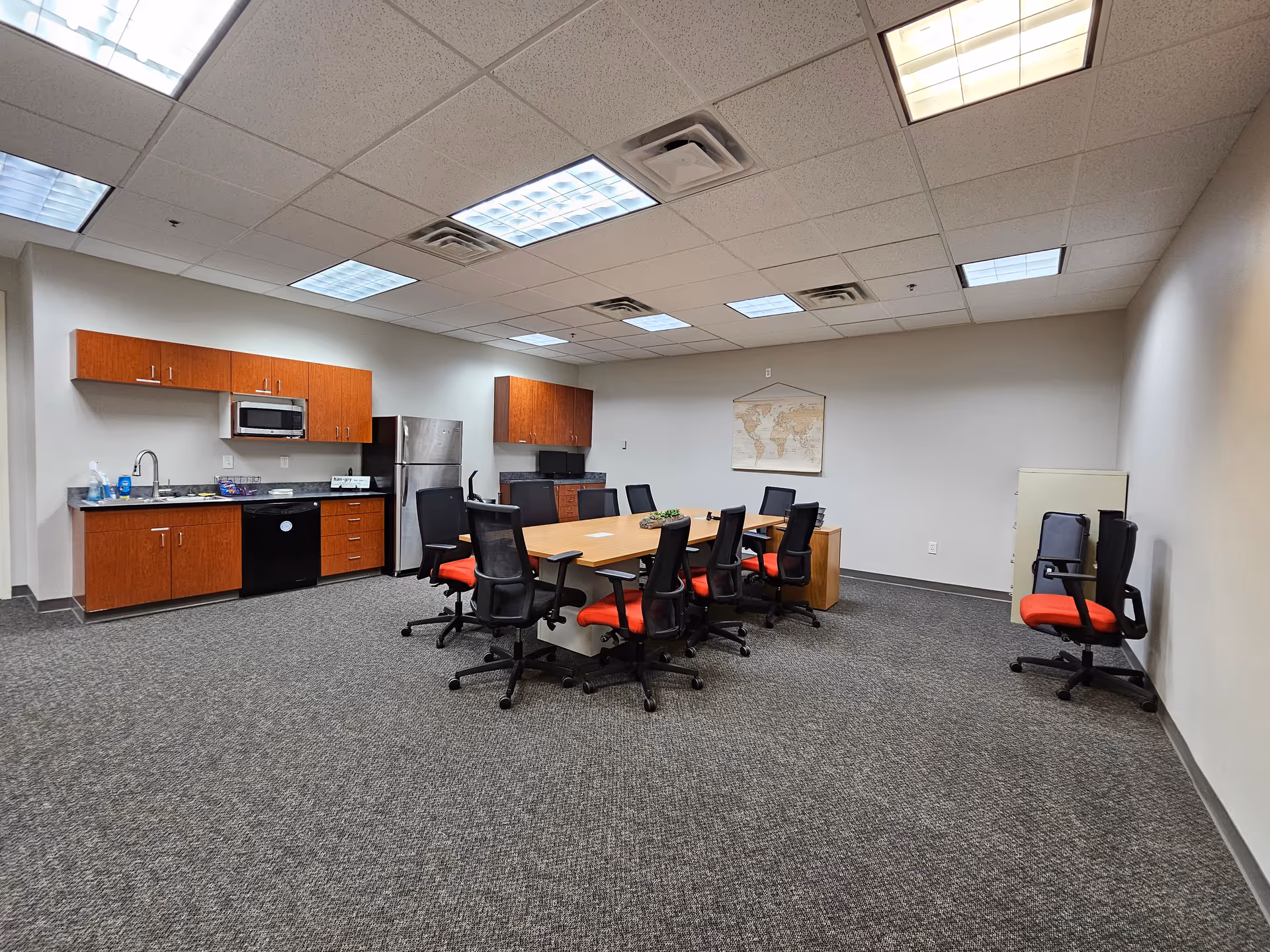 Interior conference room with long table, red-cushioned chairs, and kitchenette.