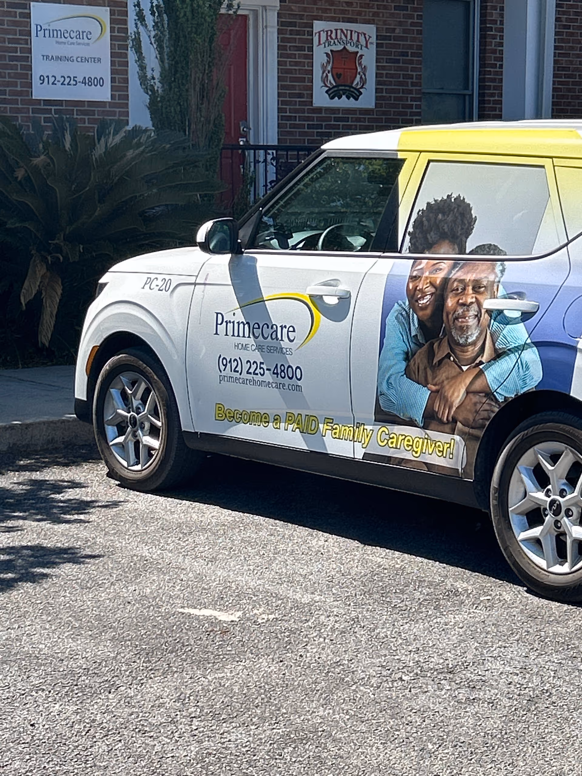 Primecare Home Care Services van parked outside a brick facility with training signs.