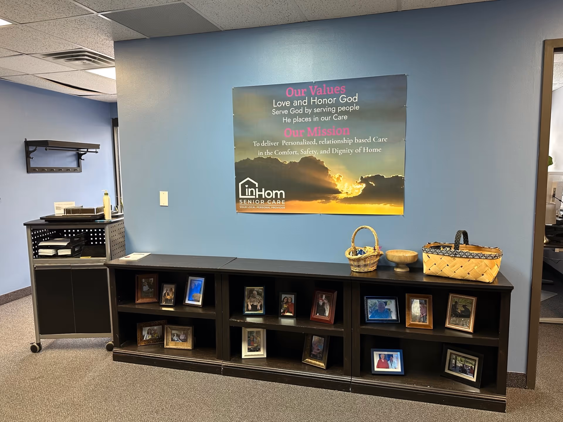 Blue-walled common area with a poster, photo frames, and baskets on a dark console.