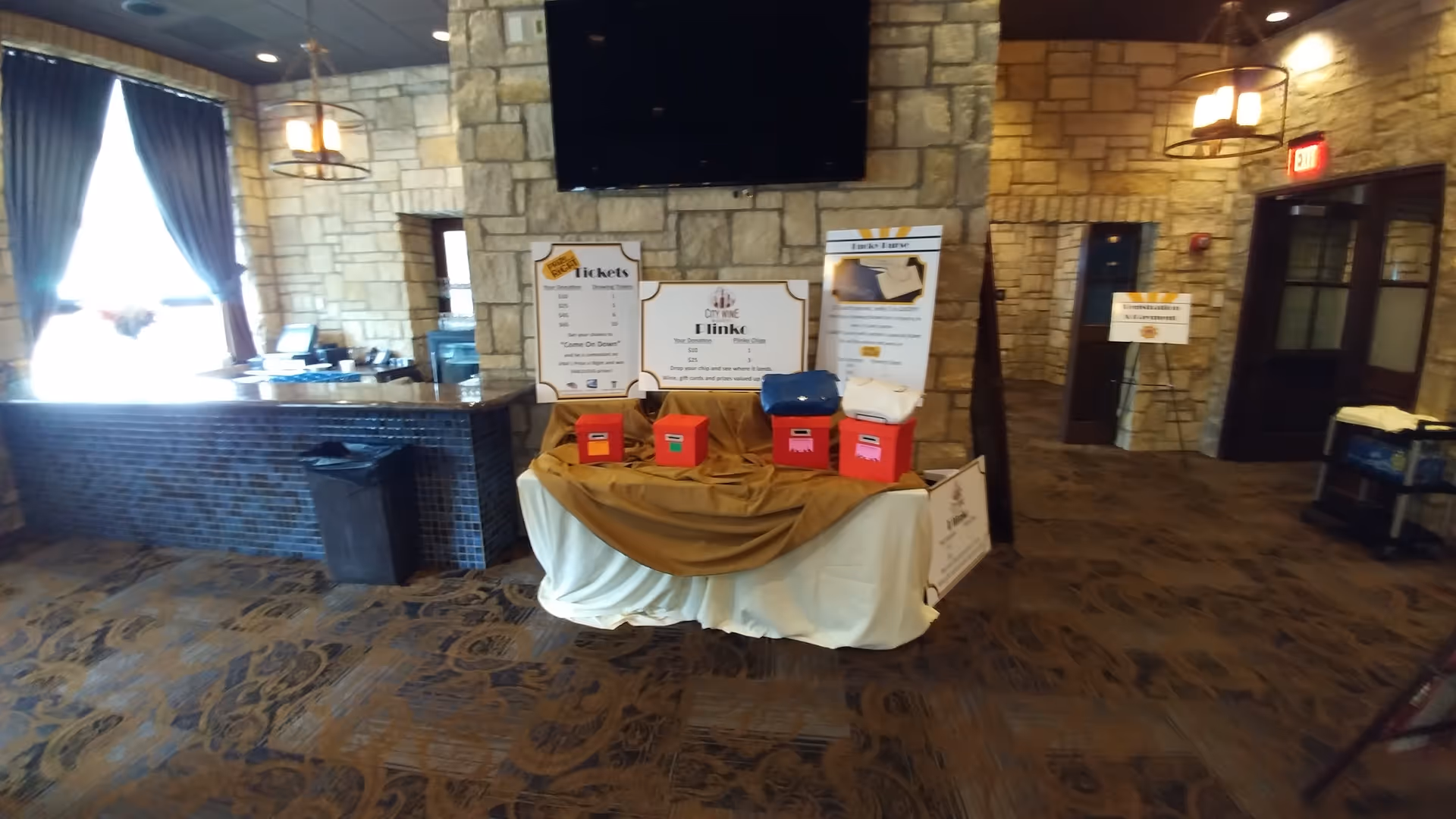 A lobby area with stone walls, a central information table with labeled signs and colored bins.