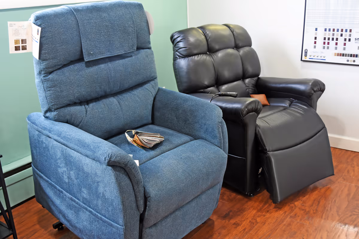 Blue fabric recliner and black leather chair in a showroom-like interior.