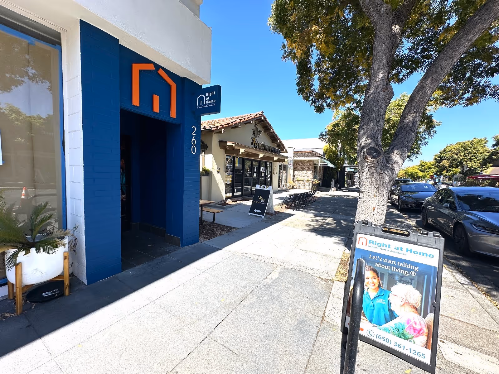 Exterior view of Right at Home facility with blue doorway and sunlit sidewalk.