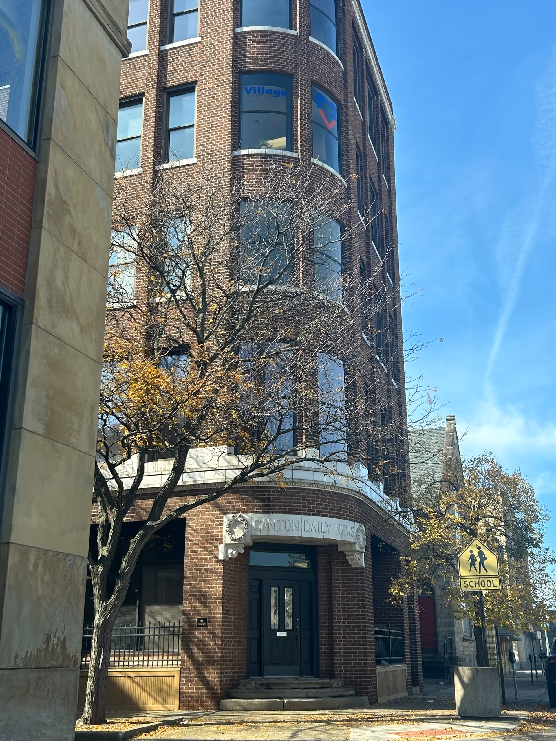 Brick building facade with arched windows and a Village Caregiving sign near the entrance.