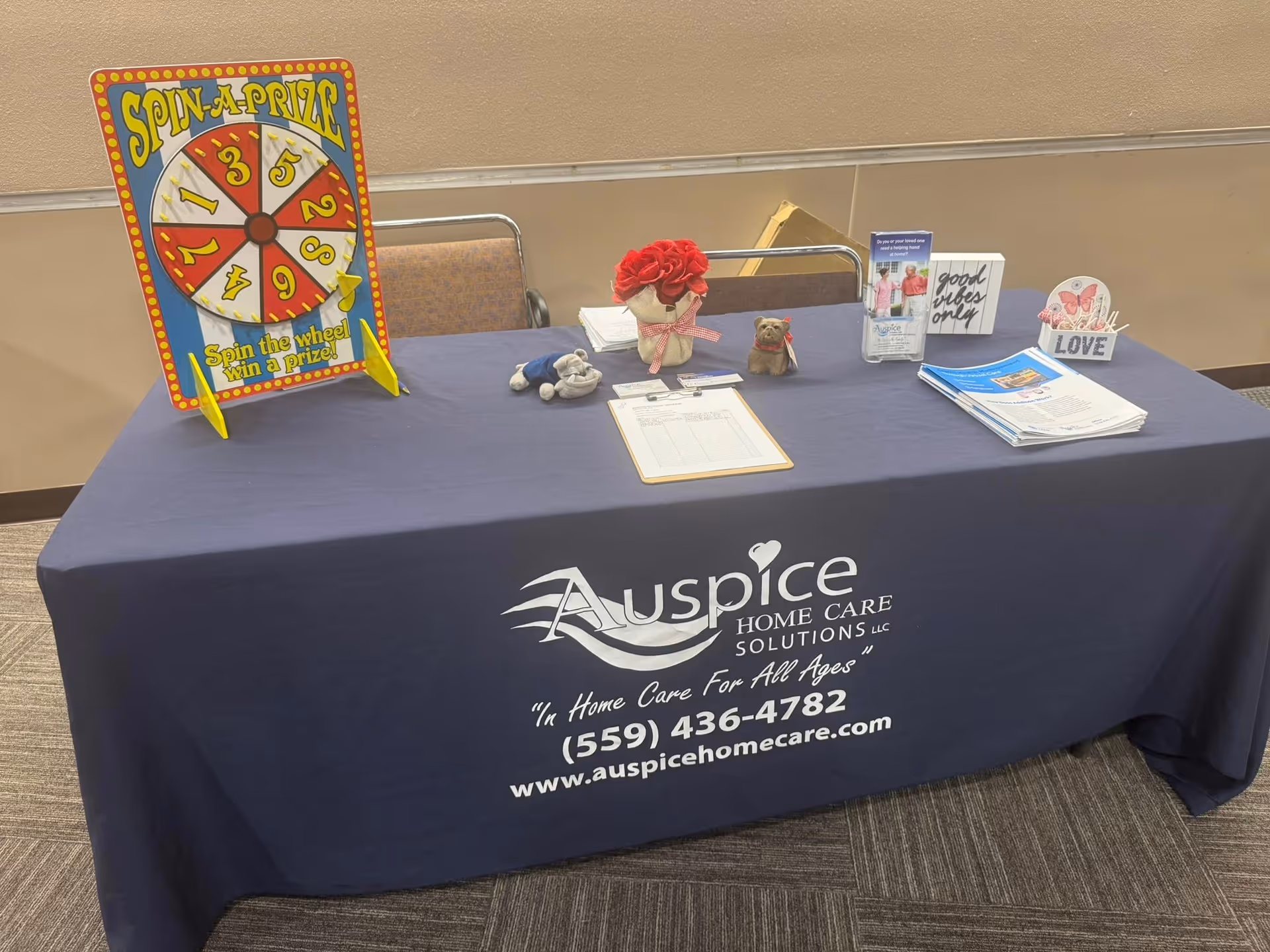 Promotional display table for Auspice Home Care with a spin wheel and brochures indoors