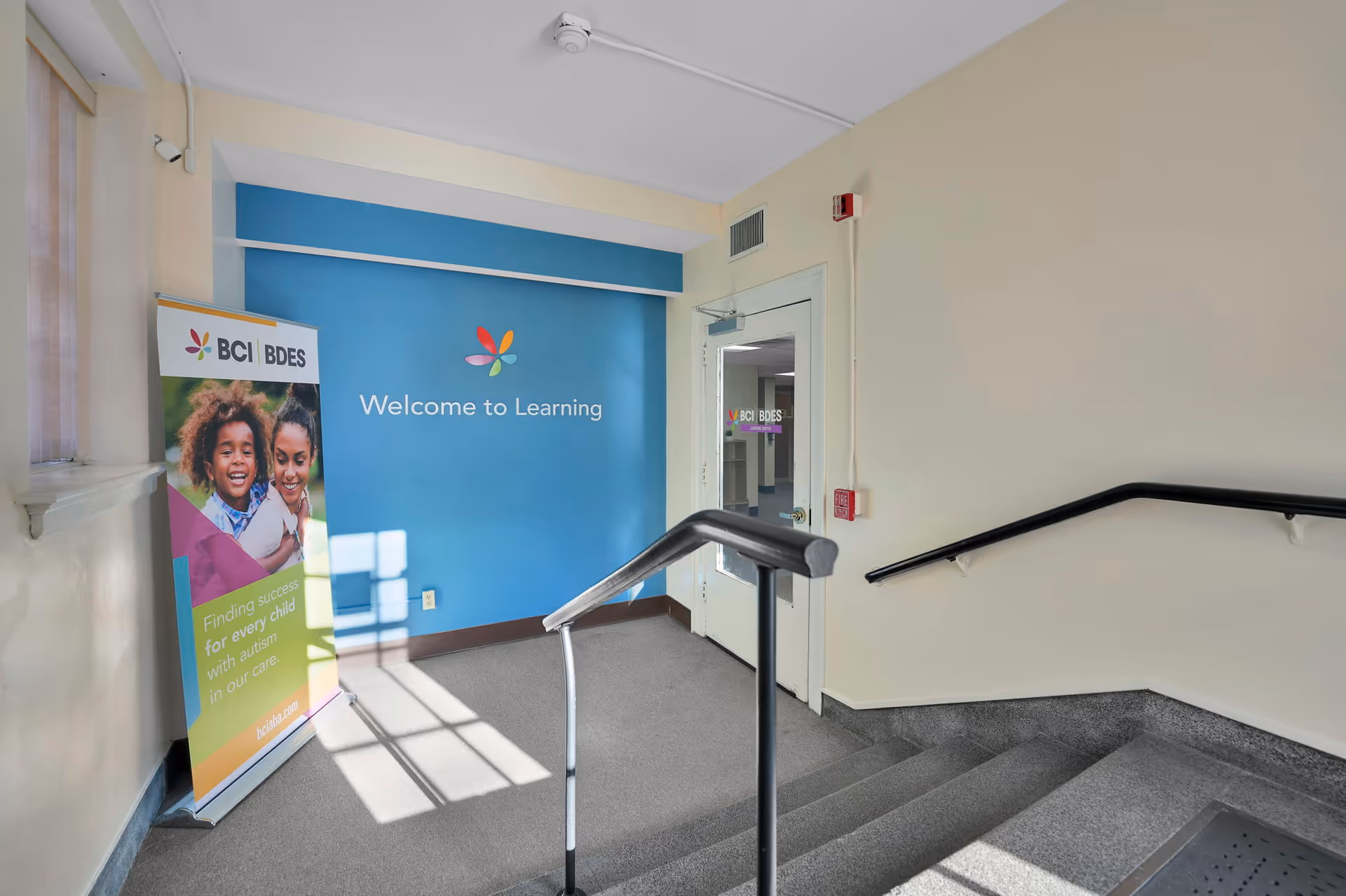 Interior stairwell features a blue learning wall and a banner with children.