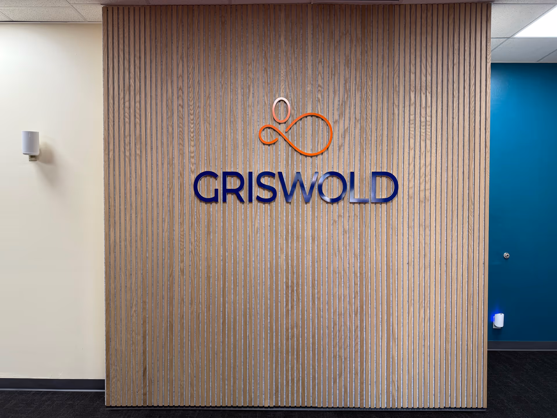 Wood-paneled interior wall displaying Griswold logo and orange emblem in a lobby.