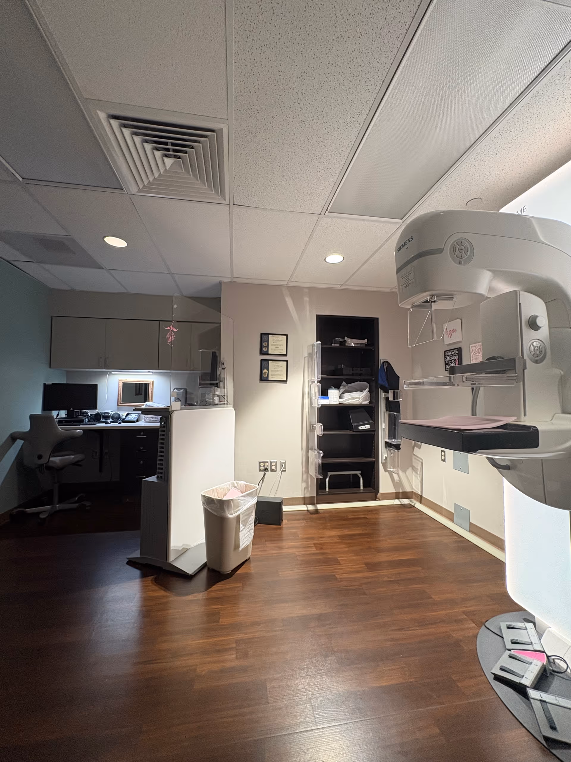 Saint John Hospital radiology room featuring a large imaging scanner, desk, cabinets, and wooden floor.