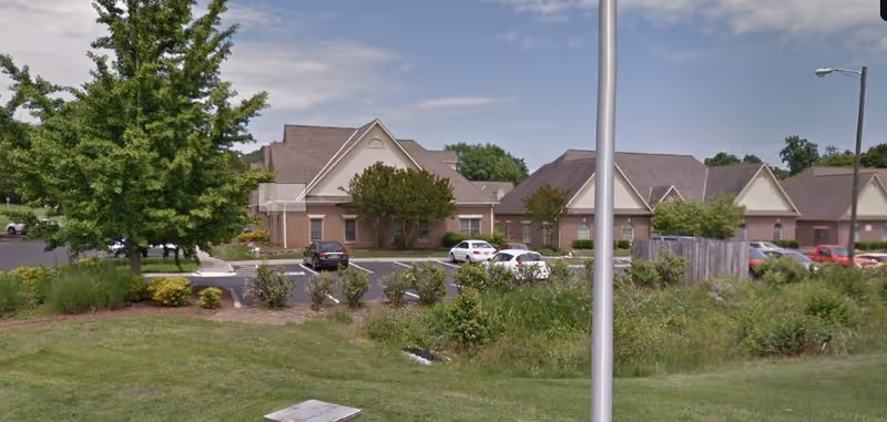 Exterior view of CNS Cares senior living facility with parking, trees, and landscaping.