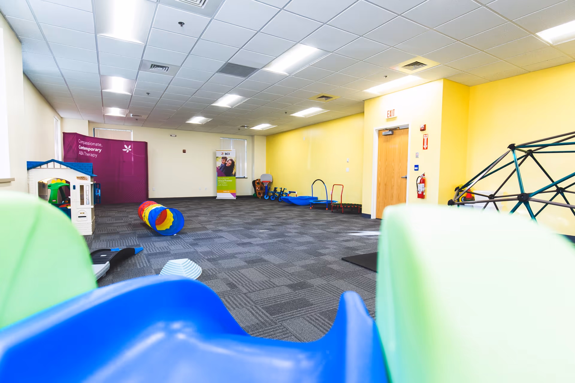 Bright indoor activity room with colorful play equipment and mats