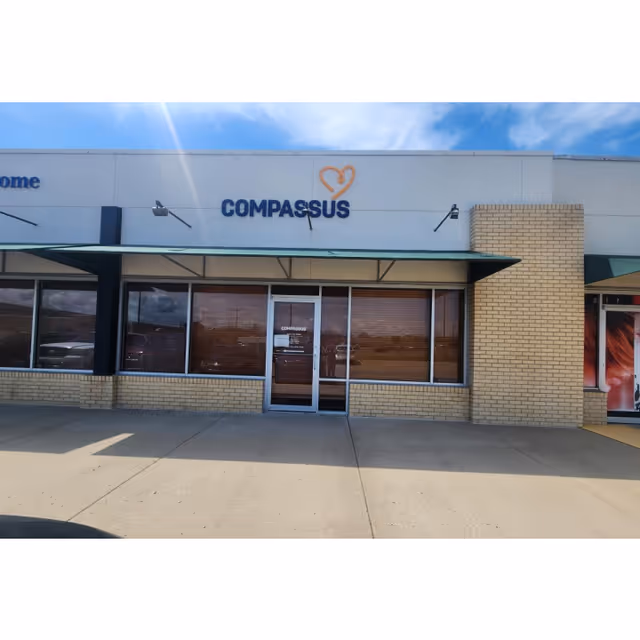 Front of a Compassus facility with glass doors and brick facade.