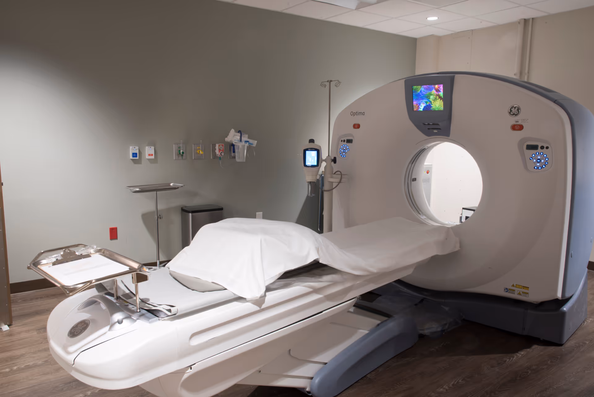 GE Optima CT scanner in a hospital imaging room with patient table