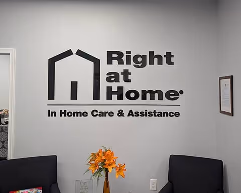 Interior lobby with Right at Home logo, two dark chairs, and orange flower centerpiece.