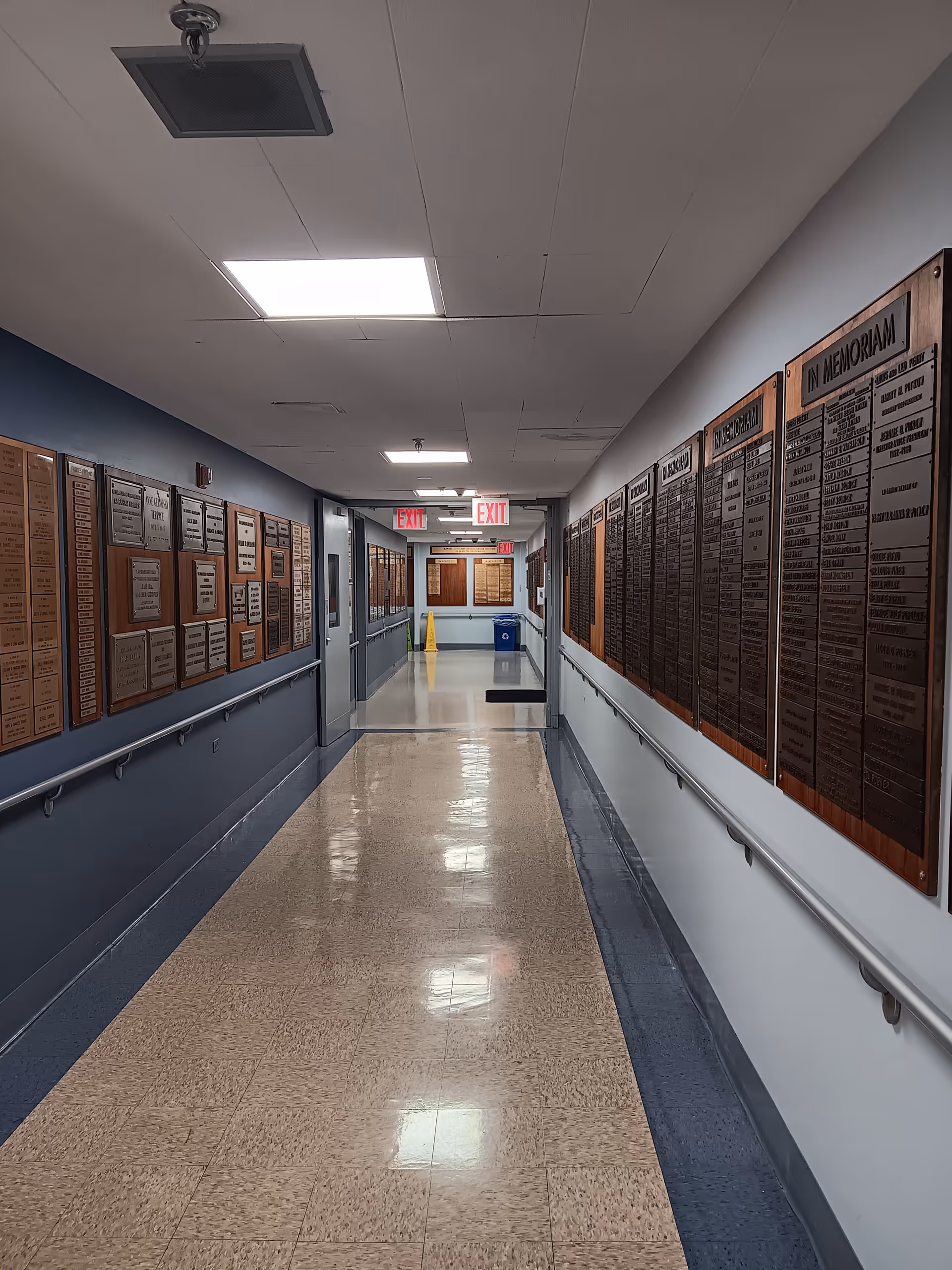 Long hospital corridor lined with memorial plaques along both walls.