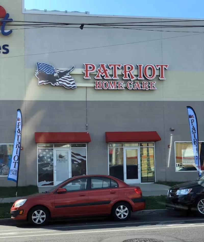 Exterior view of Patriot Home Care building with red awnings and parked cars.