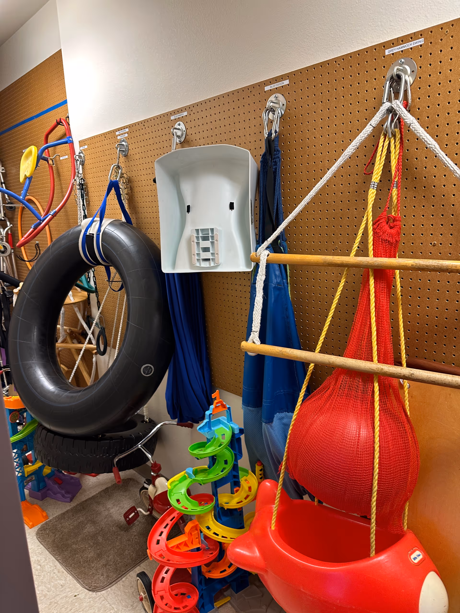 Interior storage space with pegboard wall and colorful therapy and play equipment.