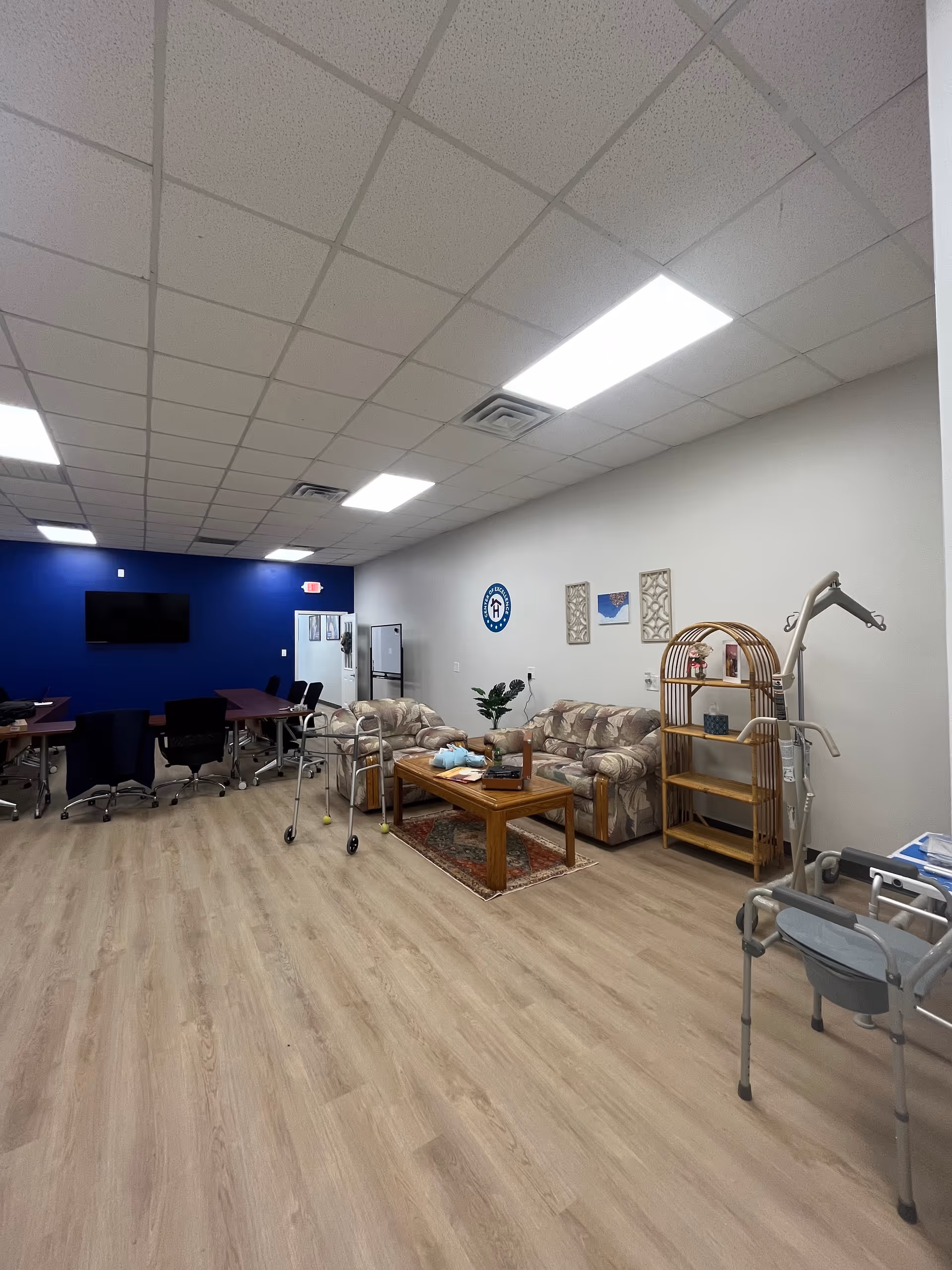 Interior common area with couches, coffee table, walker, and blue accent wall in a senior facility.