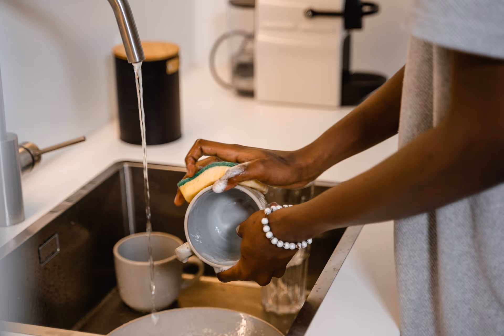 Person washing dishes at a sink in a modern kitchen.