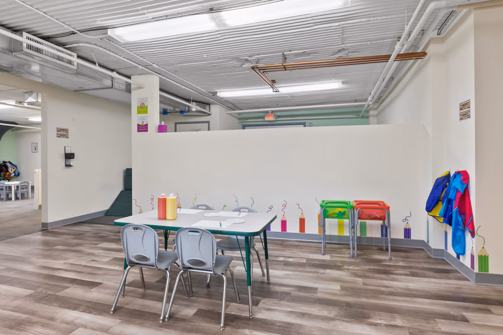 Bright dining area with a table, chairs, and colorful wall decorations.