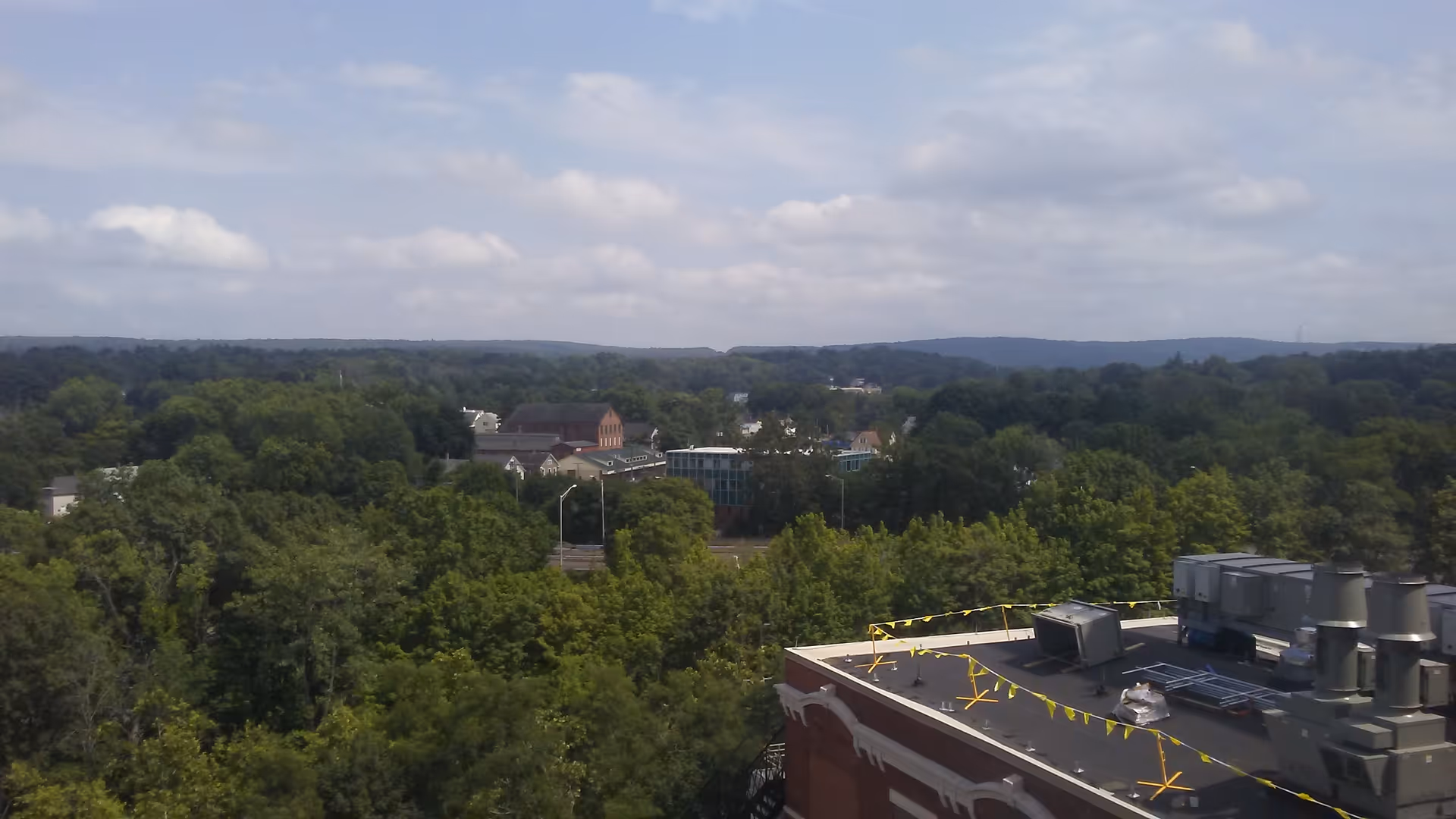 Rooftop view of a hospital with HVAC equipment overlooking a dense tree-covered area.