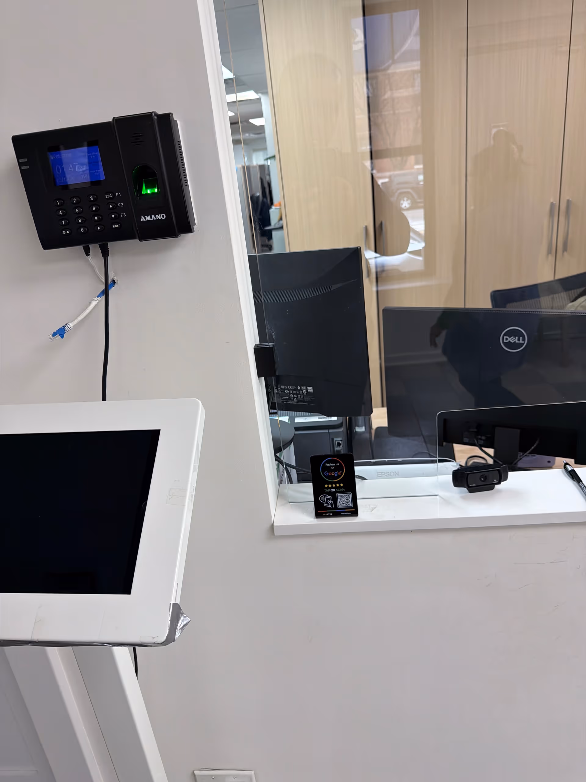 Interior reception area featuring a wall keypad, window pass-through, and multiple monitors.