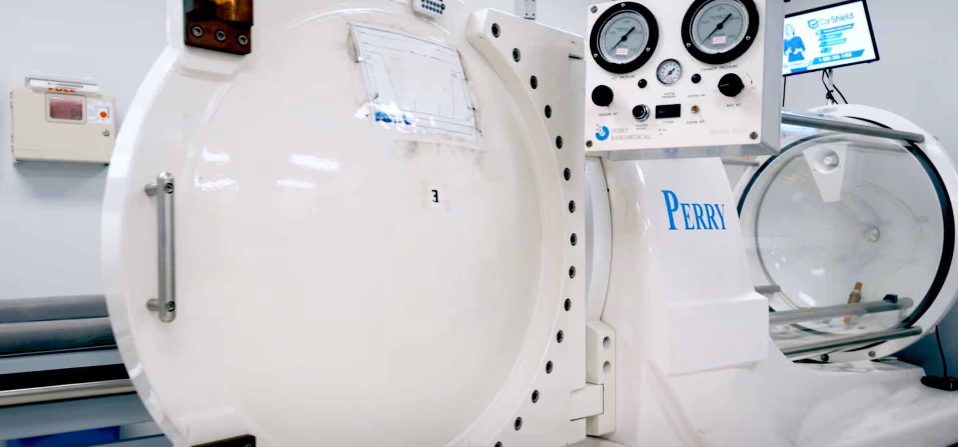 White hyperbaric chamber with gauges in a clinical wound care room.