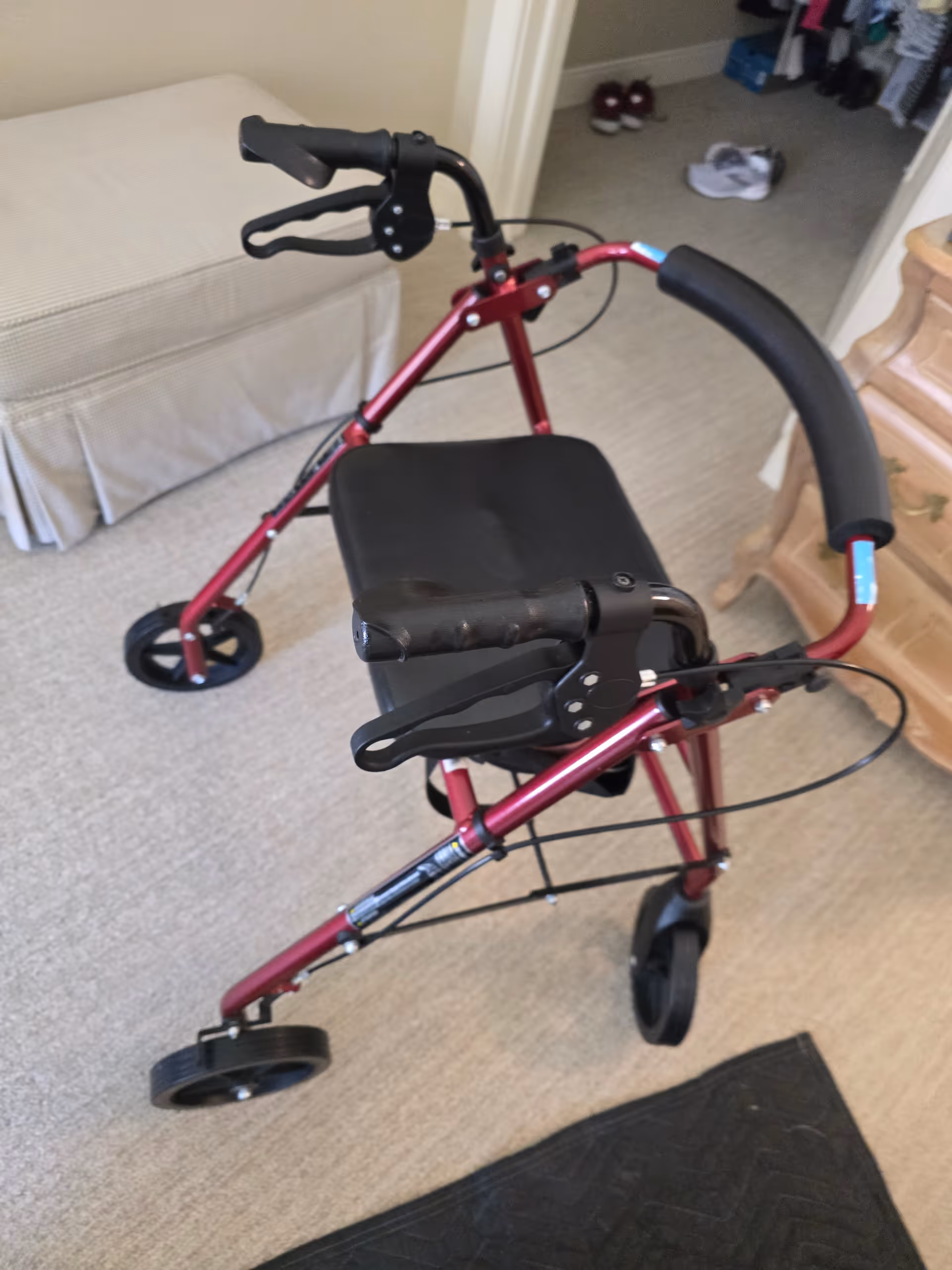 Red folding walker with a padded seat sits in a carpeted senior living room