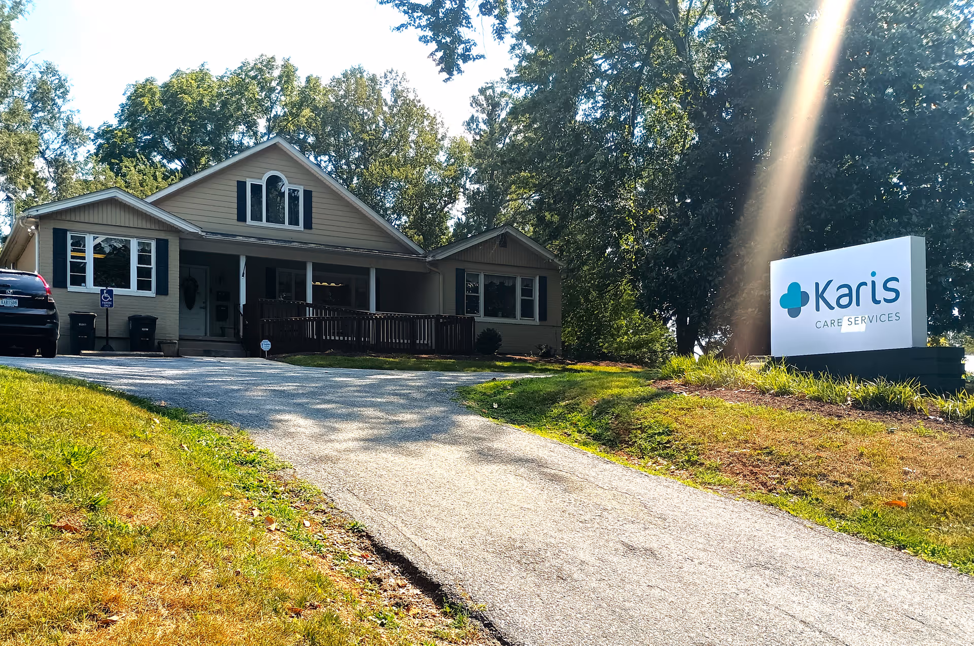 Exterior view of a Karis Care Services facility with a driveway and sign.