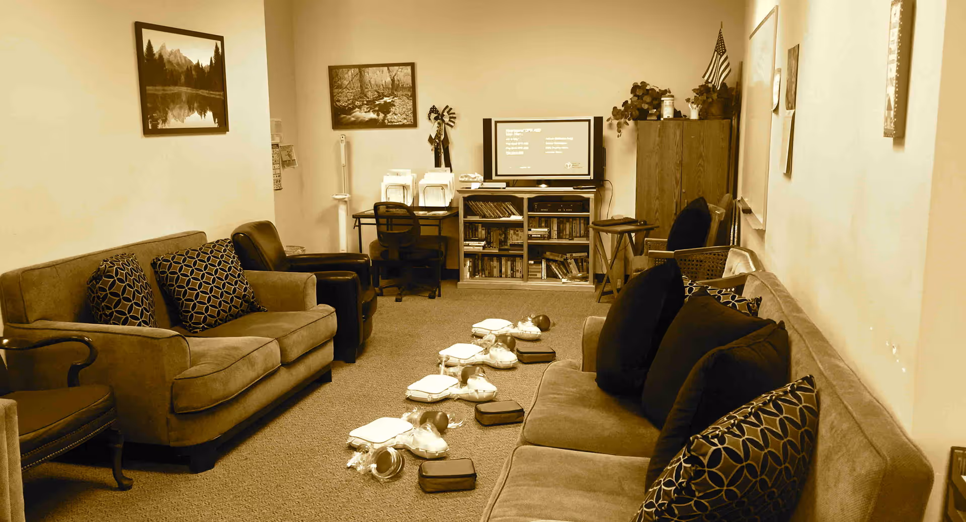 Cozy senior living lounge with sofas, pillows, a TV, books, and training equipment.