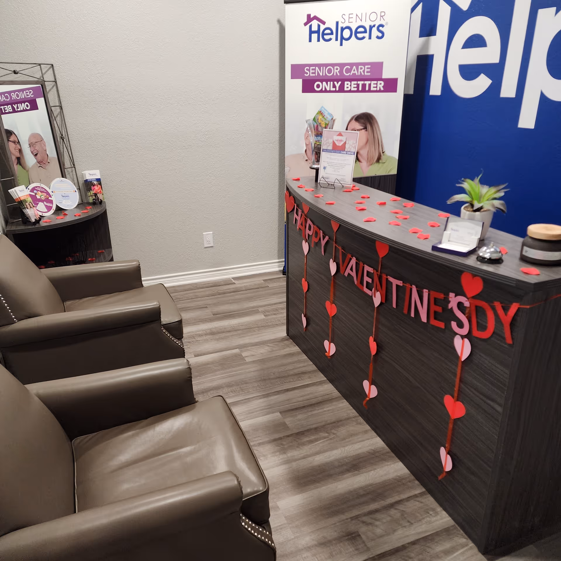 Reception desk with red heart garlands and Senior Helpers branding in a lobby.