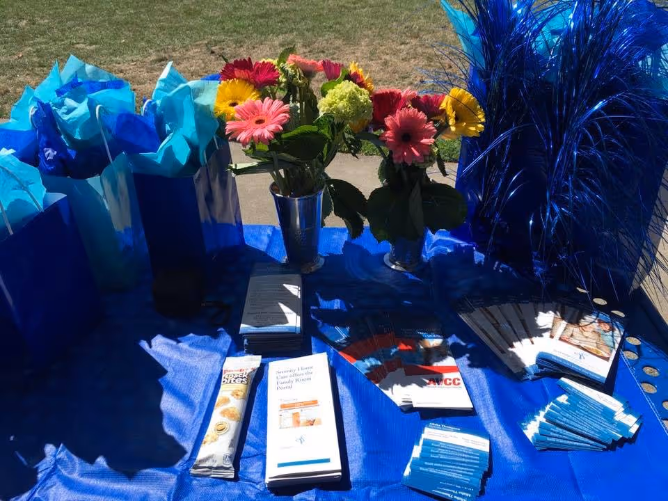 Outdoor display table with blue gift bags, flowers, and brochures.
