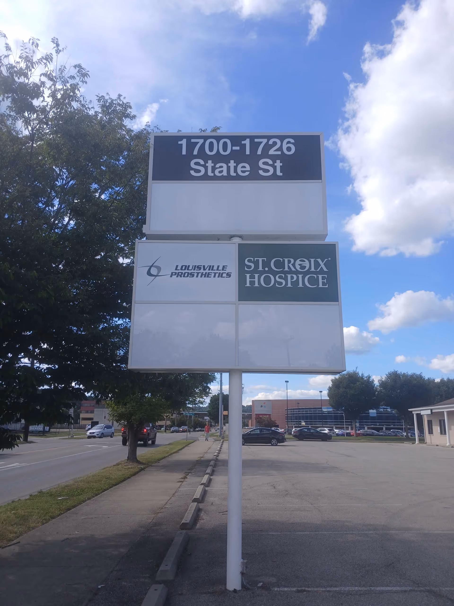 An outdoor sign reads St. Croix Hospice with Louisville Prosthetics beside a parking lot.